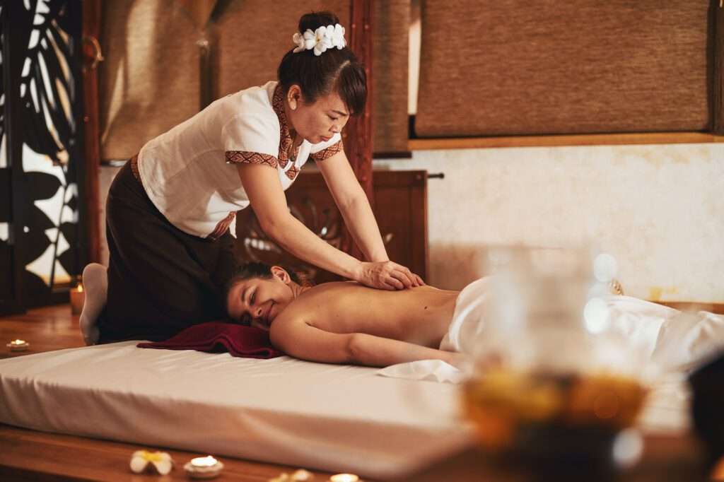 Trained massagist applying stones to skin of enjoying woman